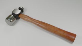 a hammer with a wooden handle on a white surface