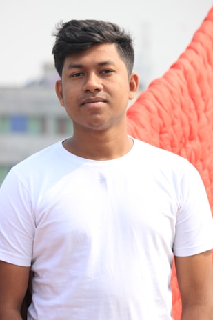 Close-up of a man wearing a plain white t-shirt outdoors.