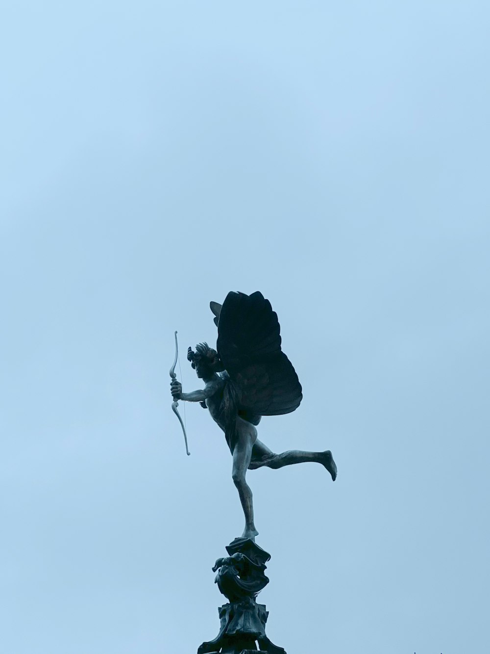 a statue of a woman holding a bow on top of a building