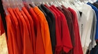 A variety of t-shirts in different colors and sizes hanging neatly on a rack
