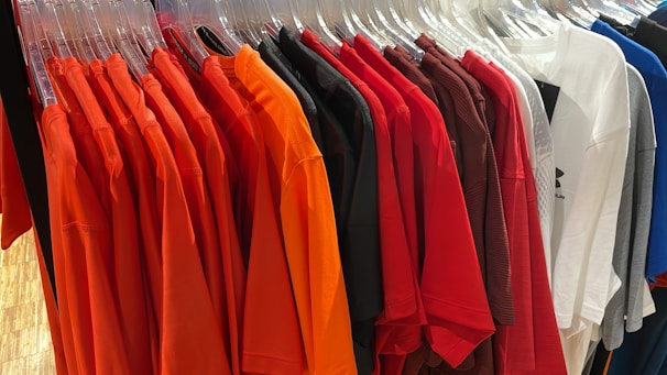 A vibrant display of classic plain t-shirts hanging on a rustic wooden rack.