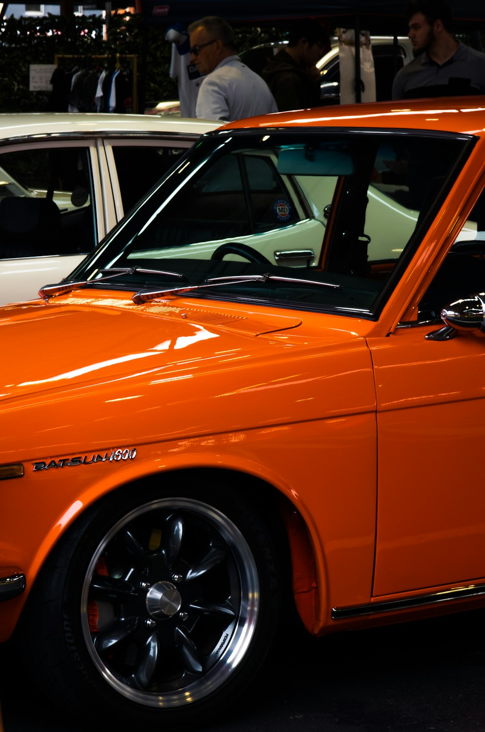 an orange car parked next to a white car