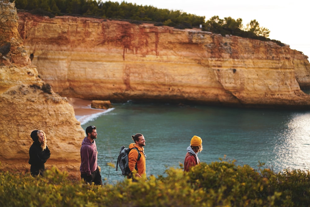 a group of people standing on top of a cliff next to the ocean