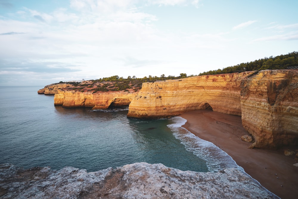 a rocky cliff overlooks the ocean on a sunny day