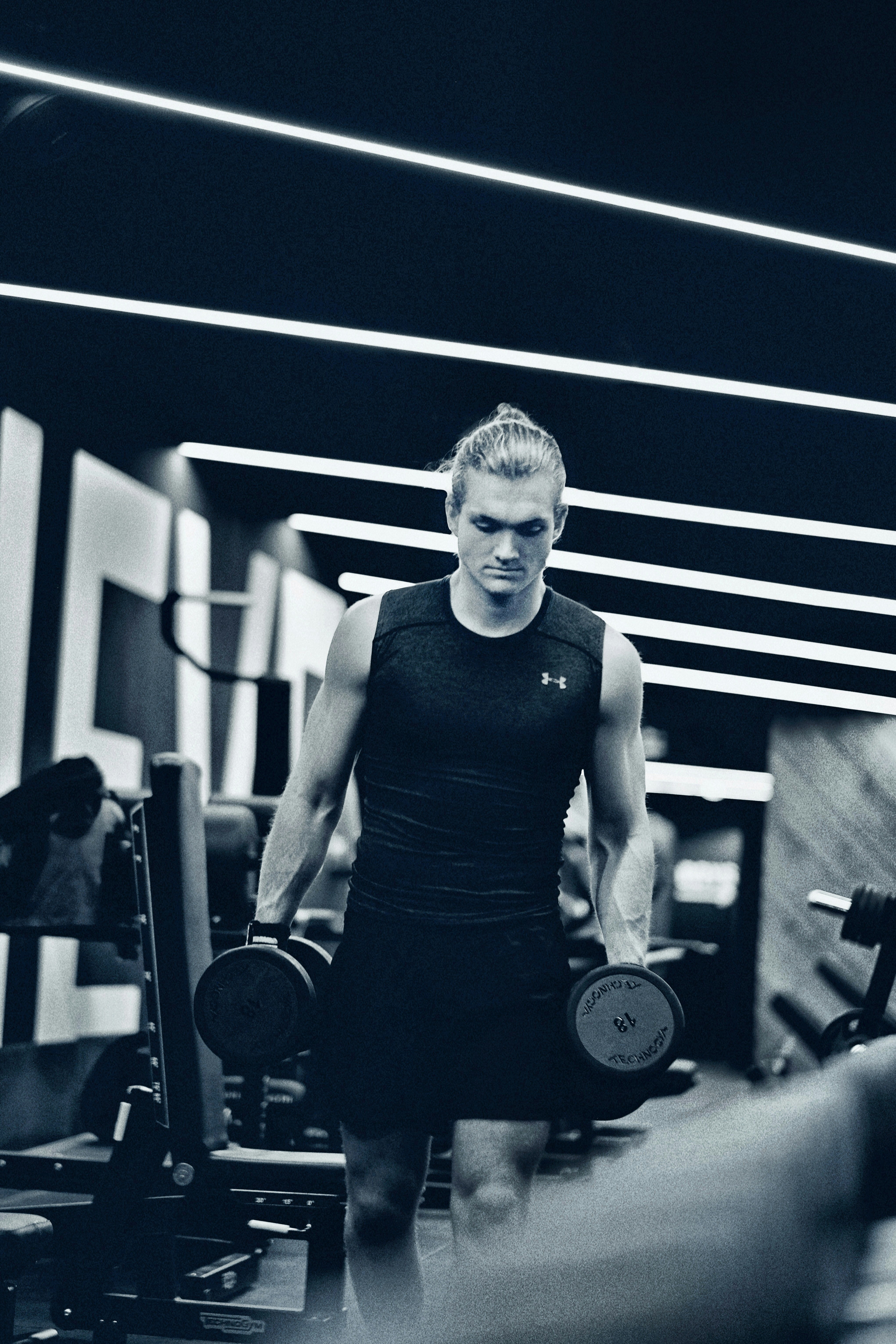 a man holding a pair of dumbs in a gym