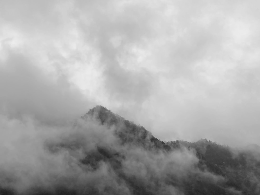 a black and white photo of a mountain covered in clouds