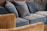 A collection of blue and brown sofas and cushions arranged in a cozy manner. The upholstery appears plush and soft, providing a comfortable seating area. The brown sofa outlines the foreground while the blue sofas and cushions dominate the background.