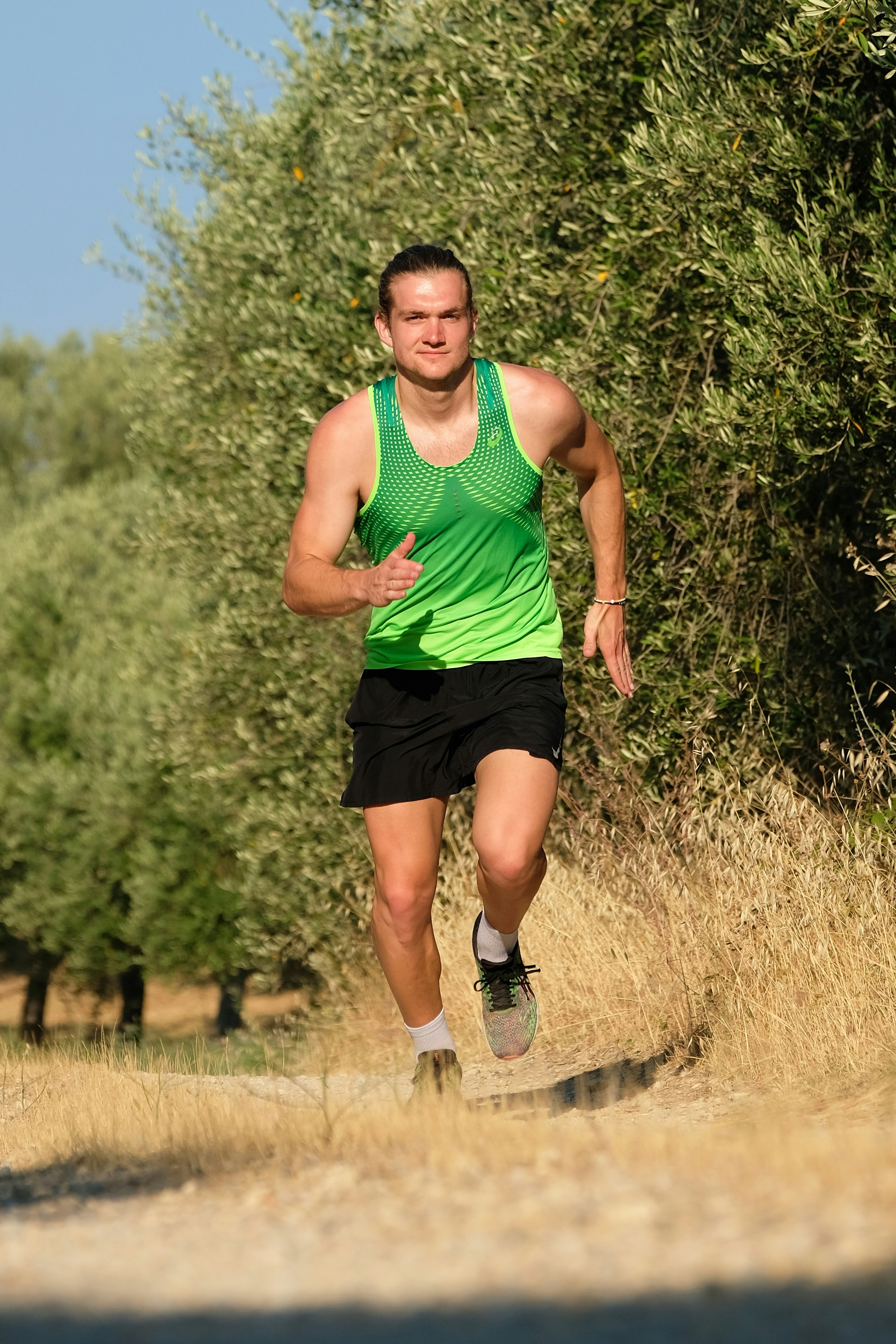 a man in a green shirt and black shorts running