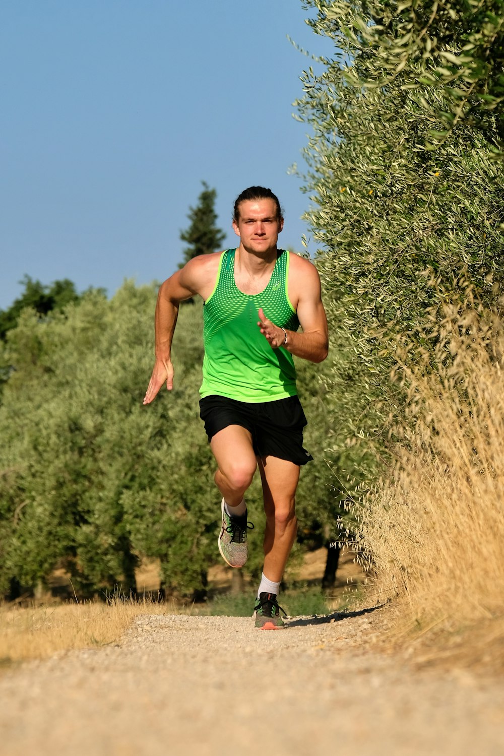 a man in a green shirt running down a dirt road