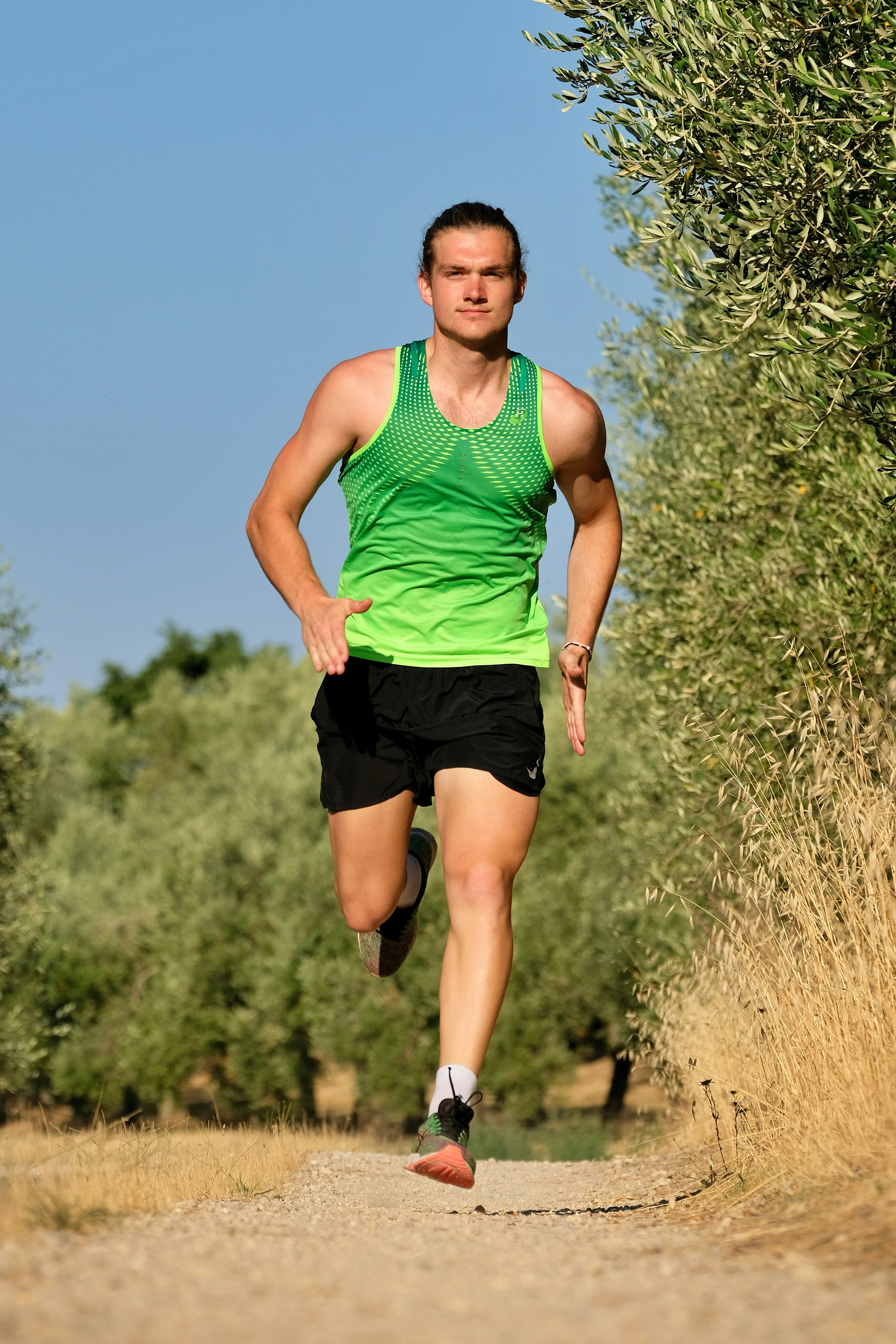a man running down a dirt road next to a forest