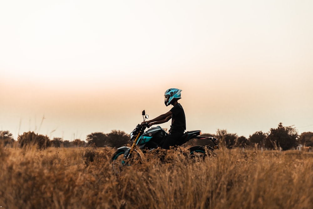 a man riding a motorcycle through a dry grass field