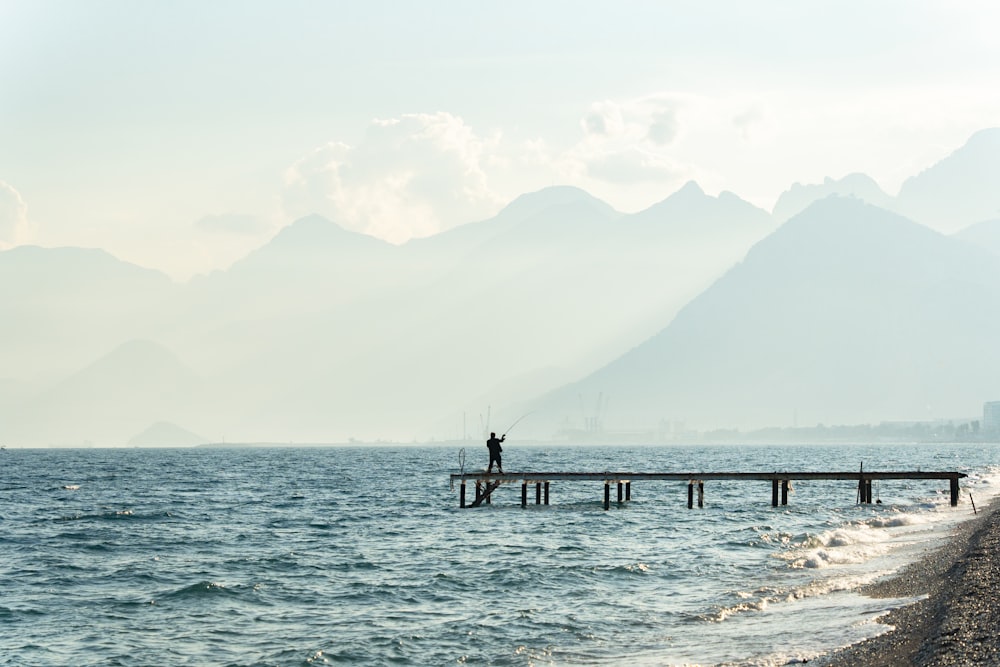 a man standing on a pier with a fishing rod