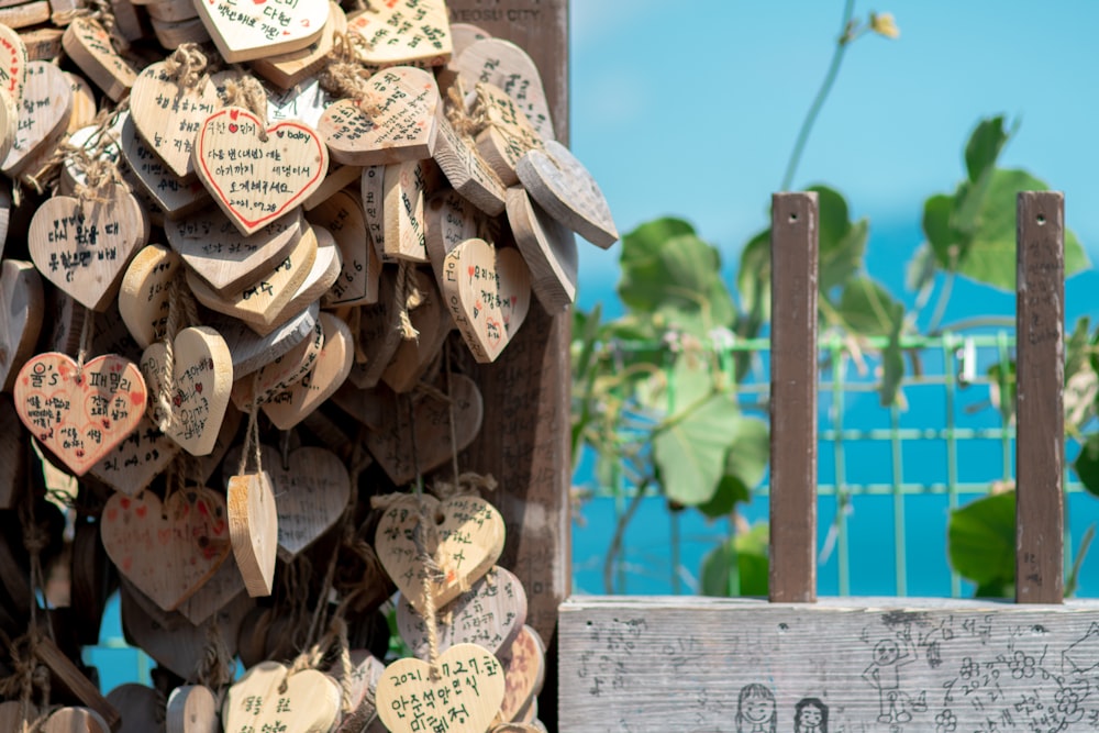 a bunch of wooden hearts hanging on a fence