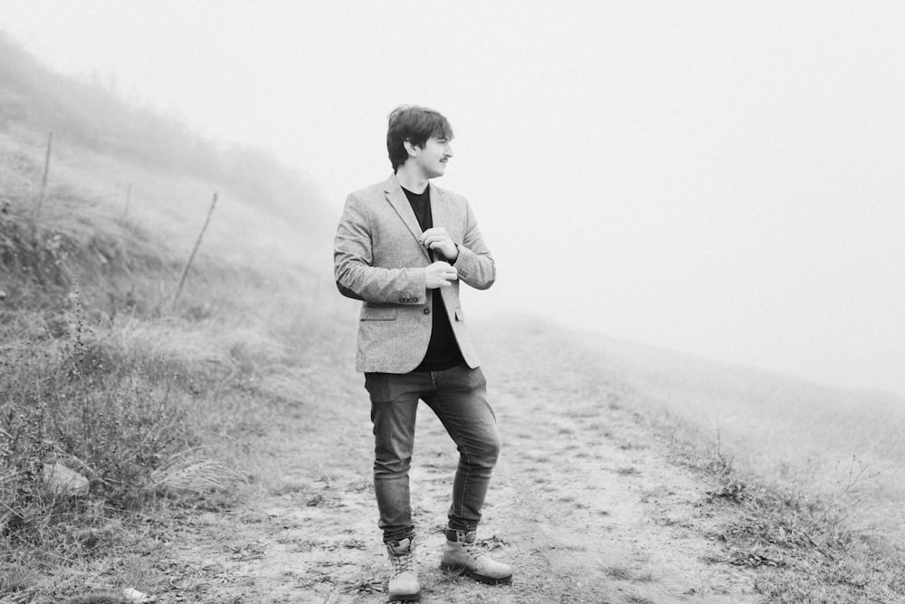 a man standing on a dirt road in the fog