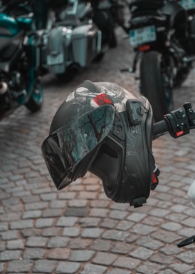A close-up of a rugged motorcycle helmet resting on a black leather jacket with the tru ikonz patch visible.