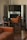 A room with elegant vintage furniture, including a brown leather sofa and green upholstered chairs with wooden frames. The chairs are positioned in front of a large ornate mirror that reflects the room's interior.