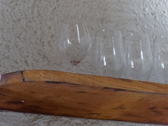 Handcrafted rustic wooden shelf mounted on a textured beige wall with soft natural light highlighting the wood grain