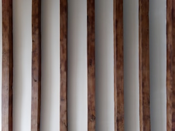 a row of wooden poles against a white wall
