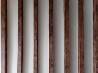 a row of wooden poles against a white wall