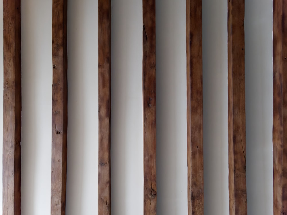 Una hilera de postes de madera contra una pared blanca