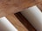 Several wooden beams arranged in a parallel alignment. The texture of the wood is rough and natural, with visible grains and varied shades of brown. These beams are placed alongside a light beige or off-white surface that runs between them.