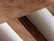 Several wooden beams arranged in a parallel alignment. The texture of the wood is rough and natural, with visible grains and varied shades of brown. These beams are placed alongside a light beige or off-white surface that runs between them.