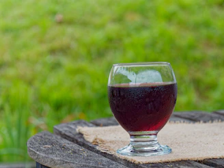 A refreshing glass of natural juice with condensation on the glass, placed on a rustic wooden table.