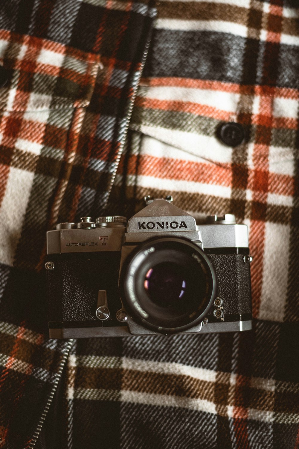 a camera sitting on top of a plaid jacket