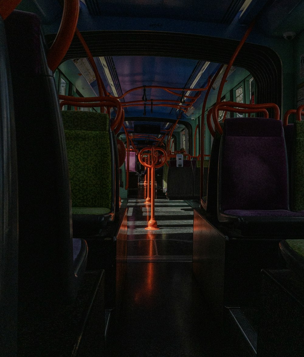 a dimly lit subway car with purple and red seats