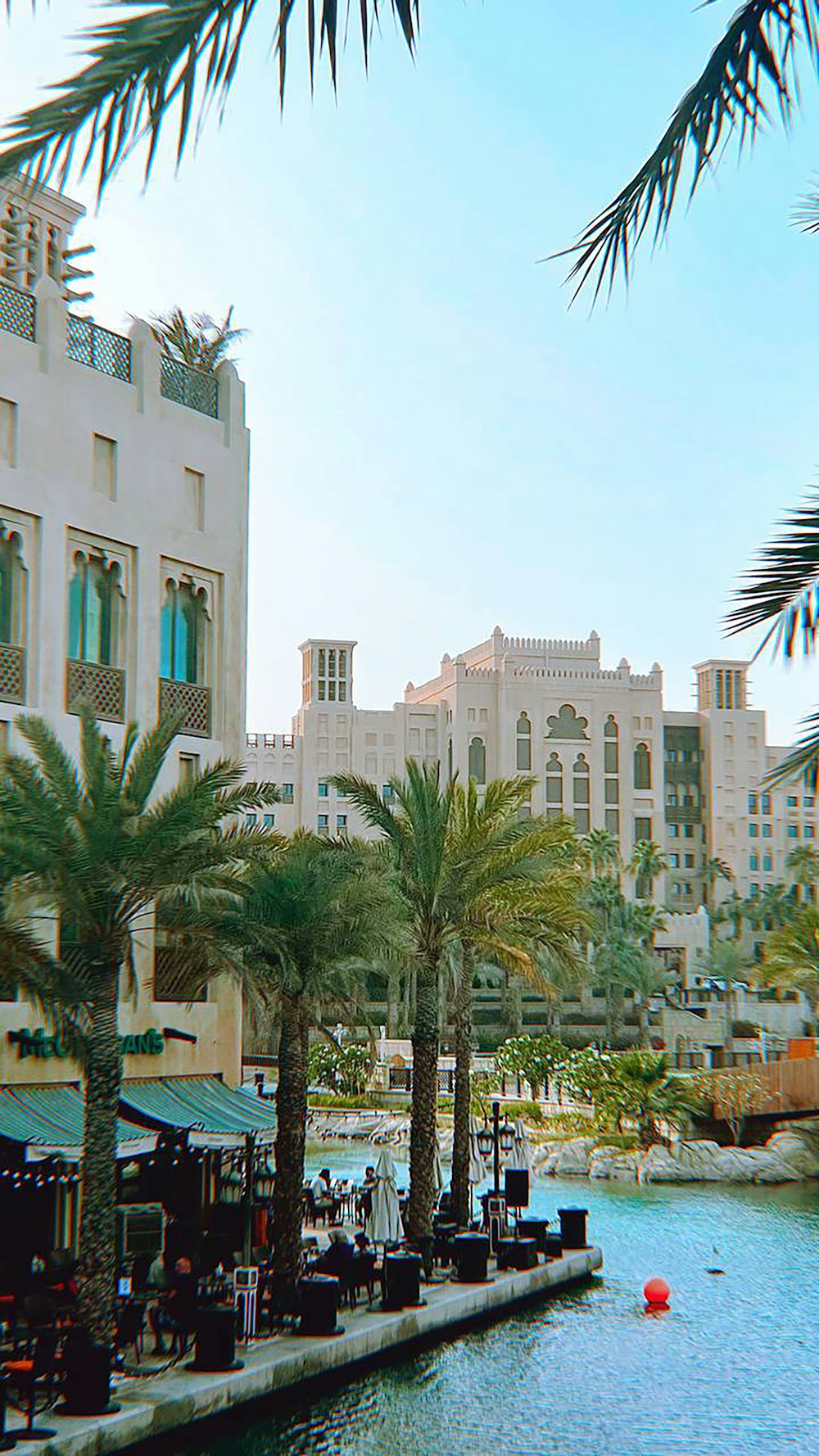 a waterway with palm trees and buildings in the background