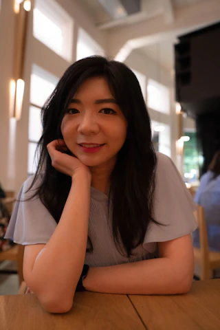 A smiling woman in her late 30s working comfortably at home with natural light.