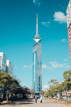 a tall skyscraper towering over a city next to tall buildings