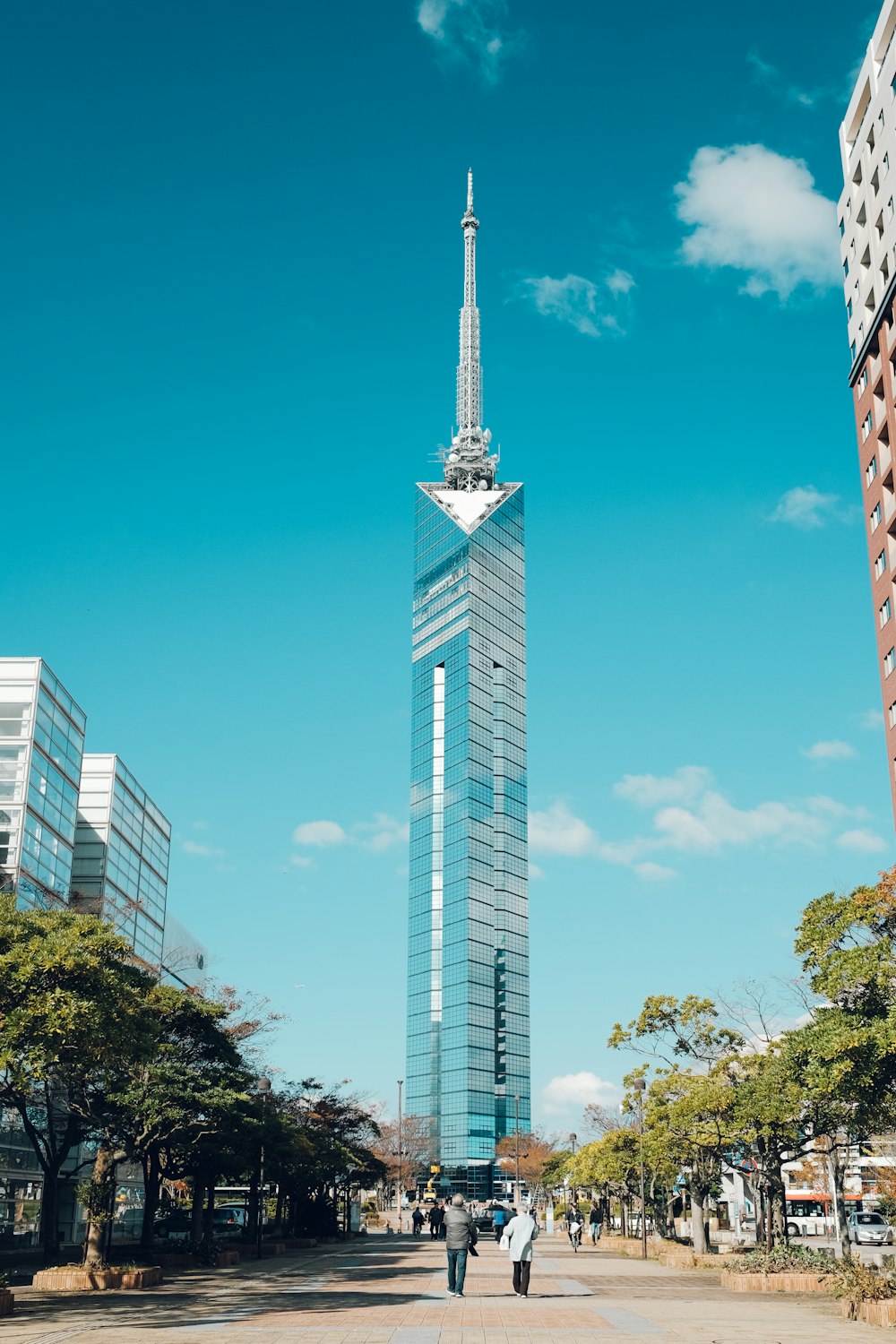 a tall skyscraper towering over a city next to tall buildings