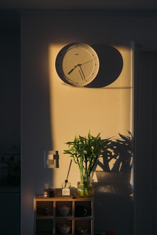 A vibrant wall clock hanging above a cozy living room fireplace, catching the afternoon light.