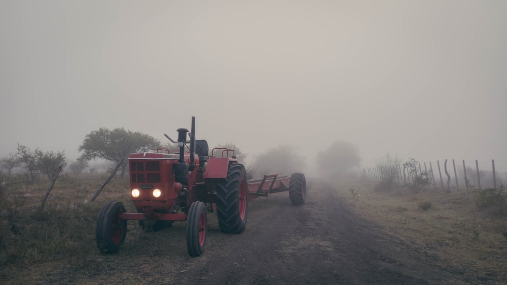 a red tractor driving down a dirt road