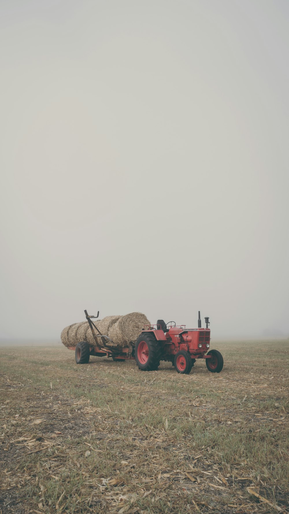 a red tractor is pulling a bale of hay