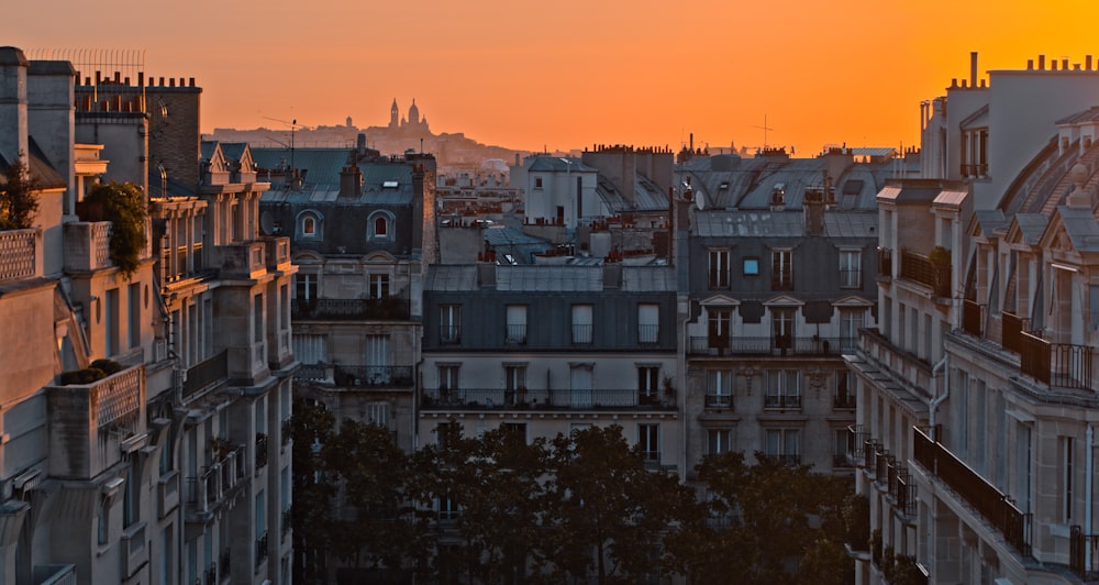 the sun is setting over a city with tall buildings