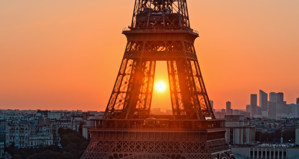 the sun is setting behind the eiffel tower