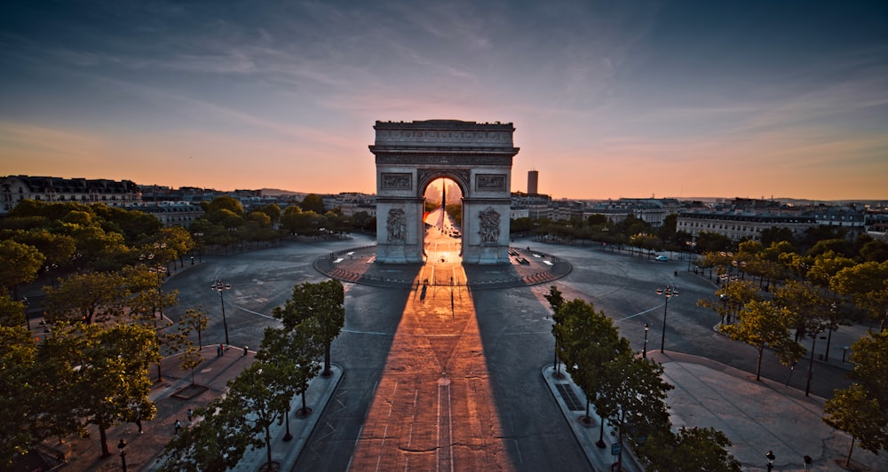 the sun is setting behind the arc of triumph