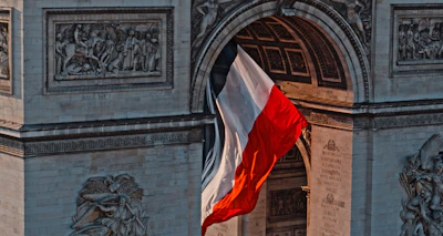 a red white and blue flag flying in front of a building