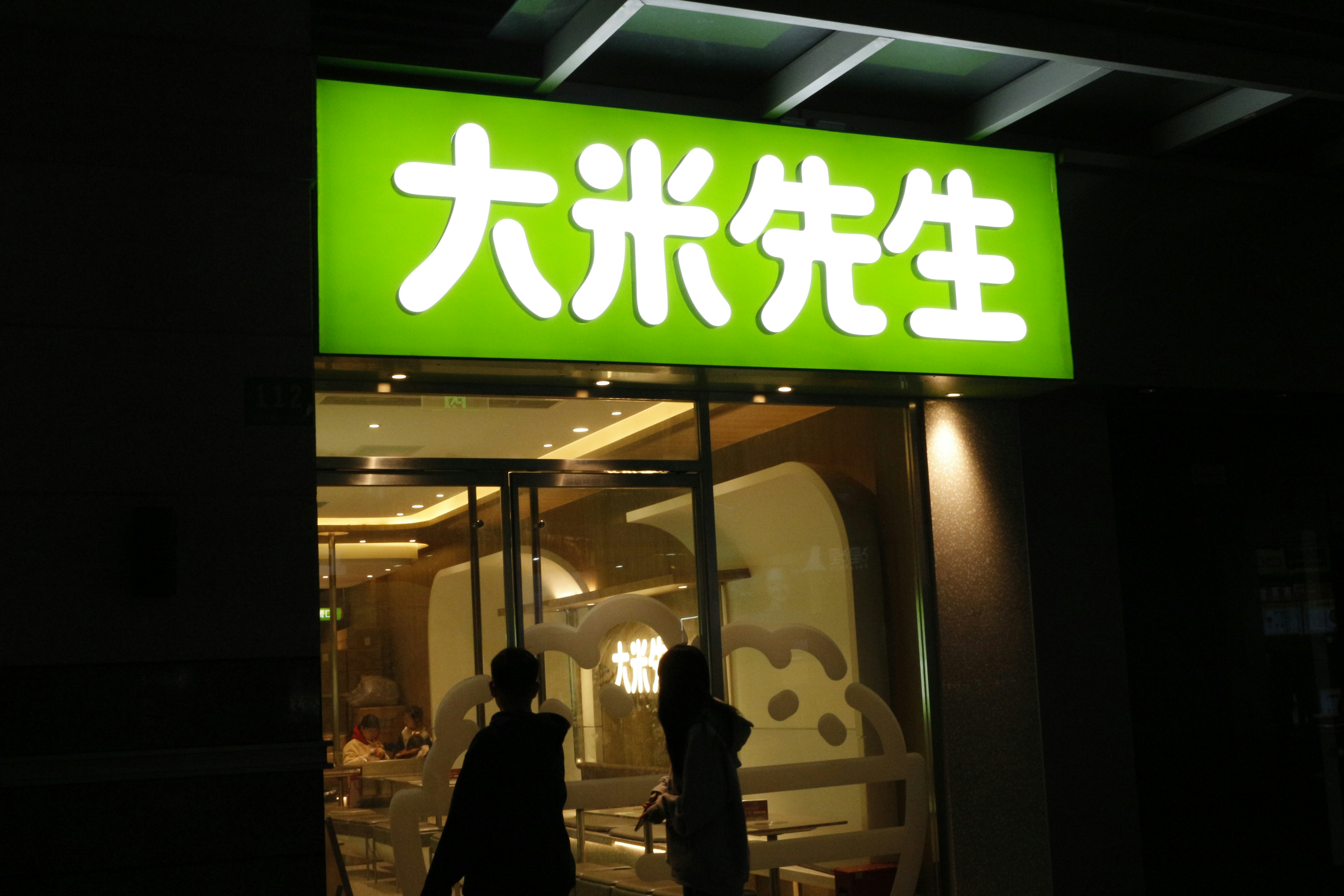 two people walking out of a restaurant at night