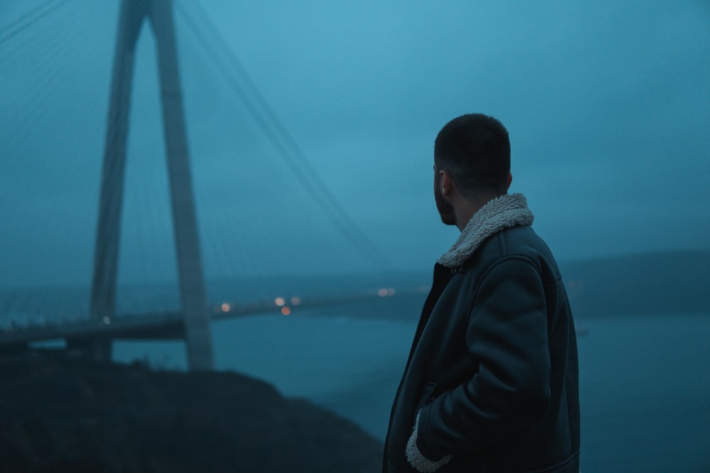 a man standing in front of a bridge at night