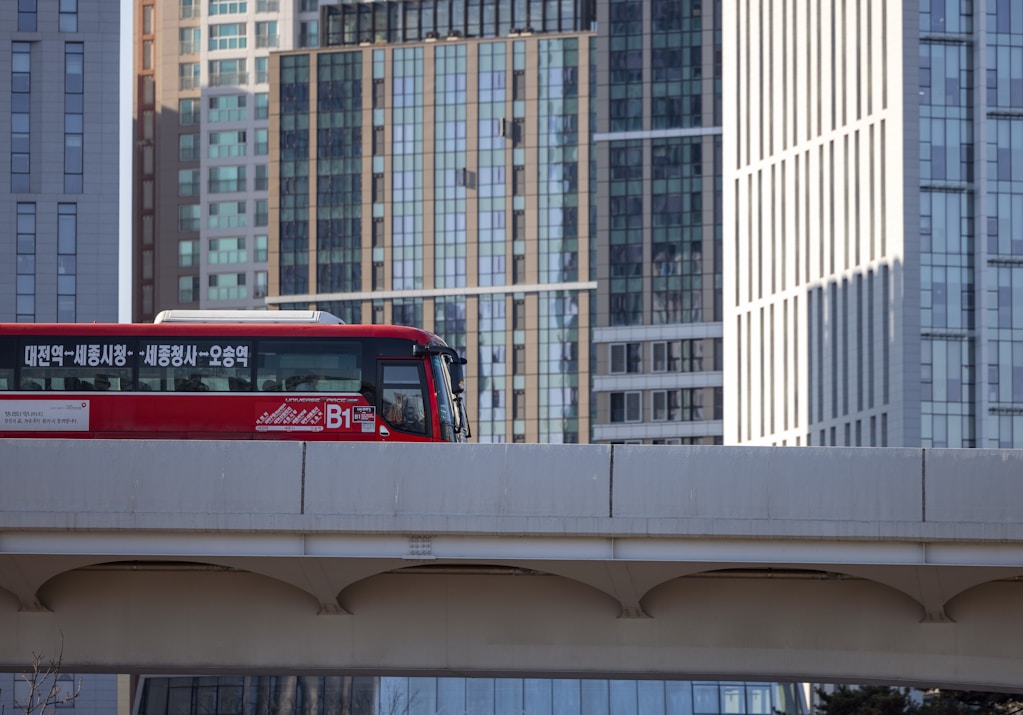 a red bus driving over a bridge in a city