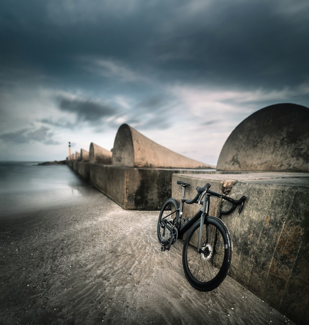 Un vélo appuyé contre un mur de béton sur une plage