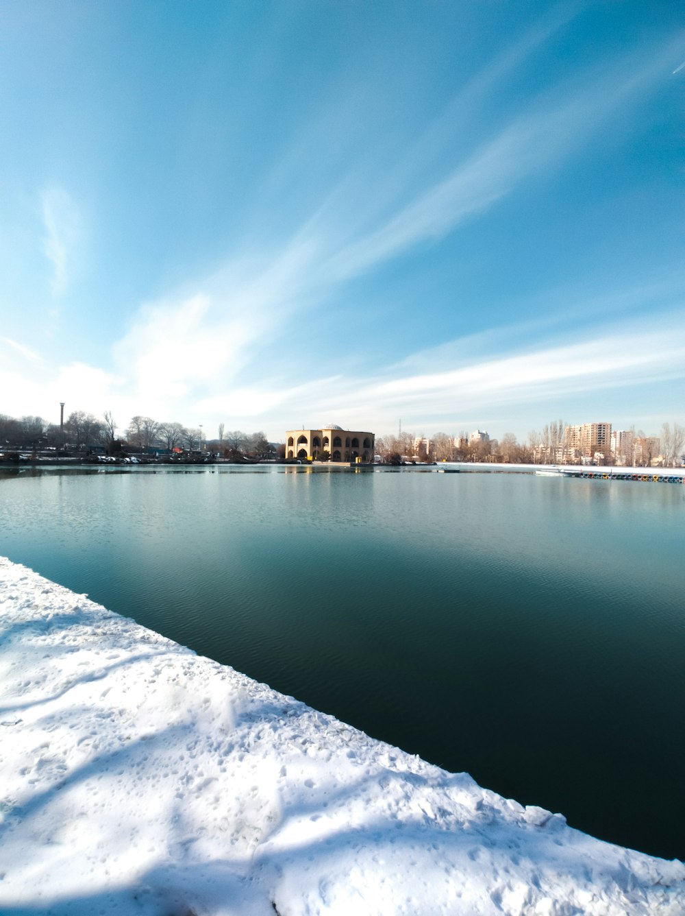 a body of water surrounded by snow covered ground