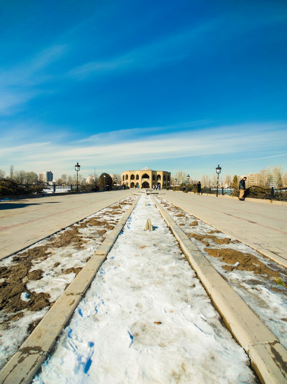 a road with snow on the ground and a building in the background