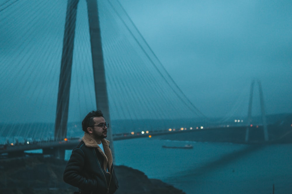 a man standing in front of a bridge at night