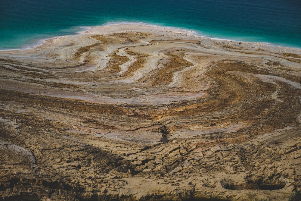 an aerial view of a sandy beach with a body of water in the background