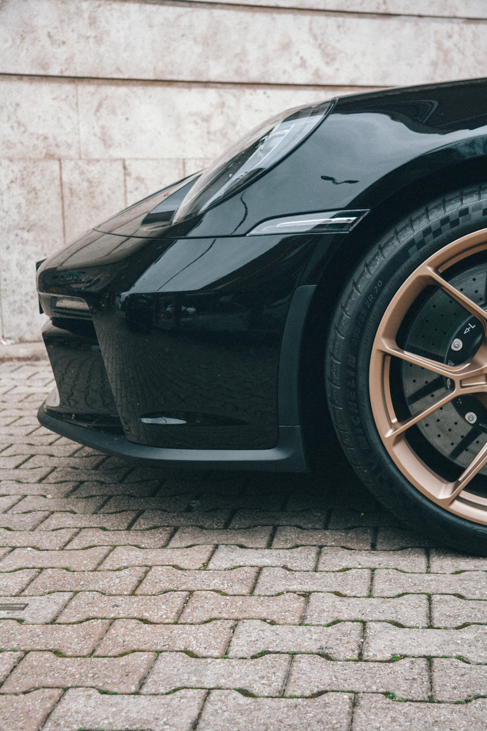 a black sports car with gold rims parked in front of a building