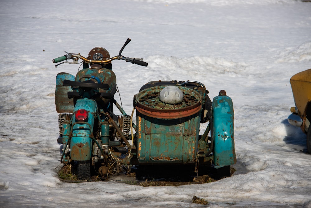 Una motocicleta azul estacionada sobre un terreno cubierto de nieve